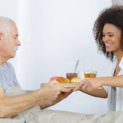 healthcare worker serving food to a senior woman