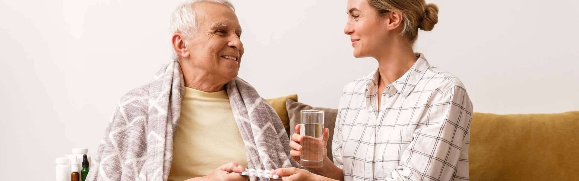 Woman is giving medicine to her sick elderly grandfather