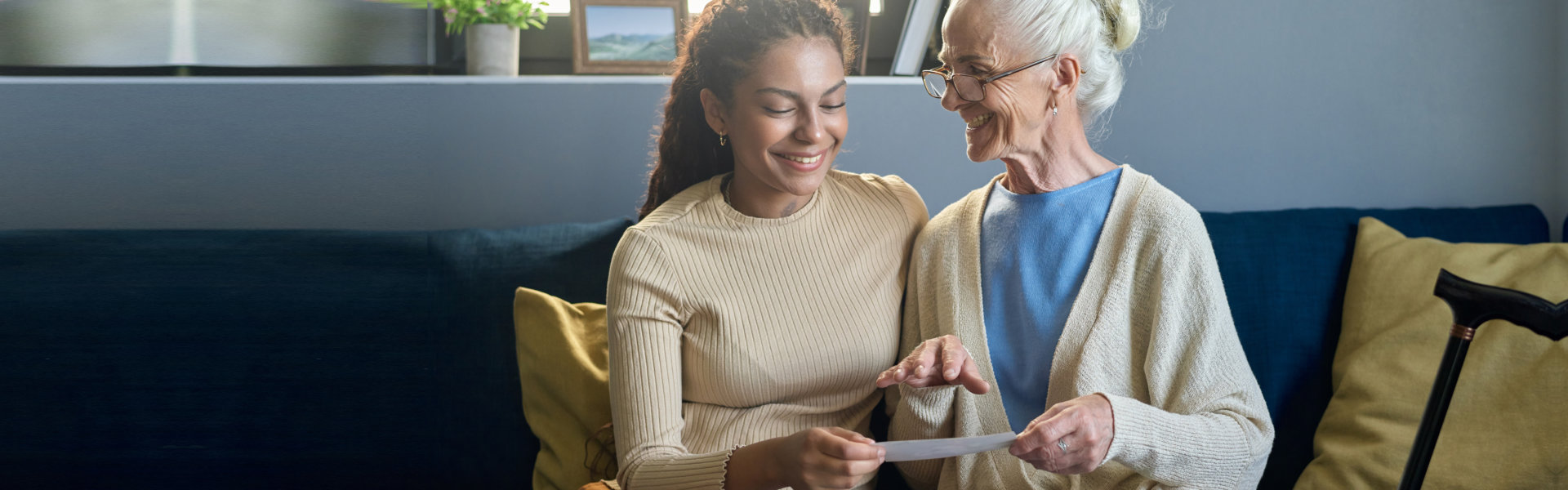 Happy old woman looking at her granddaughter while showing her family photos